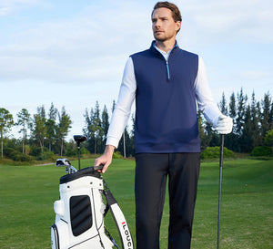 The model, wearing a Print Collar Quarter Zip Golf Vest, gazes into the distance, one hand holding a golf club and the other a golf bag.