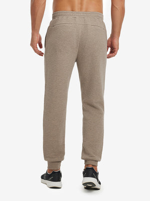 Back lower body view showing light brown heather soft sweatpants with 4 zipper pockets