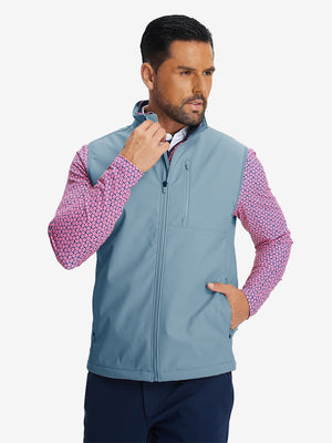 Model front half-body shot with one hand in pocket wearing sleeveless softshell fleece outdoor vests with 6 pockets in misty blue