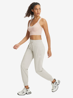 Full-body front view of model wearing women's stretch fleece lined water resistant joggers in oyster gray.