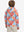 Back upper body view of model wearing youth full print stylish hoodies pullover, colorful flower.