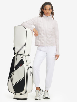 Model carrying a golf bag, wearing women's lightweight fleece-lined puffer jacket in oyster gray.