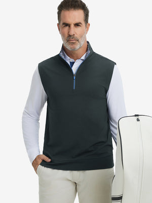 Model carrying golf bag, styled in dark grey print collar quarter zip golf vest, relaxed sporty fit.