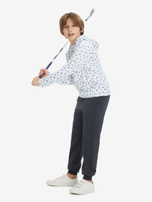 Model posing with golf club in youth full print hoodies pullover, white dog.