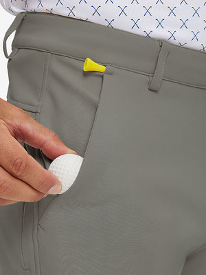 Hand placing a phone into front pocket of lightweight moisture wicking dress pants in dark khaki.