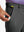 Hand placing a golf ball into pocket of water-resistant golf stretch nylon pants in dark grey.