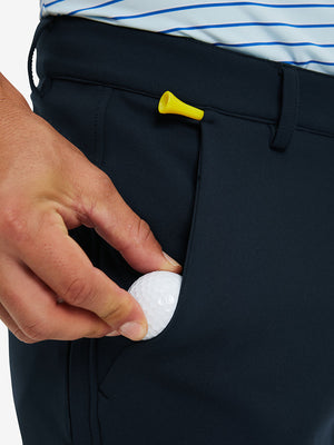 Hand placing a phone into front pocket of lightweight moisture wicking dress pants in navy.