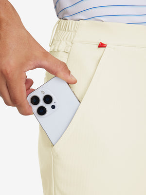 Hand placing an iPhone into pocket of lightweight flat front casual trousers in beige.
