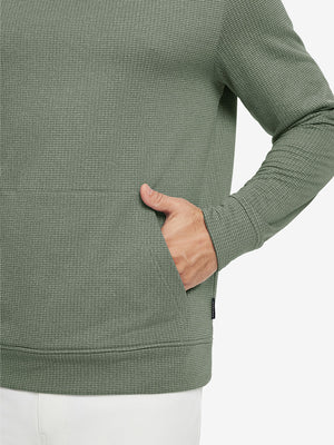 Close-up of model with both hands in pockets wearing warm fleece golf hoodies pullover green.