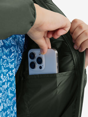 Close detail of hands inside pockets of boys windproof puffer jacket with pockets in army green.