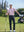 Model in light pink stripe stylish stripe jersey golf polo holding a golf club outdoors, full-body shot