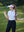 Model in white women's performance solid polo holding a golf club outdoors