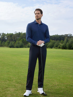Model in navy long sleeve solid jersey polo holding a golf club outdoors, full-body shot