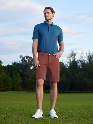Model standing hands in pockets on course in 4-way stretch performance solid shorts, cranberry