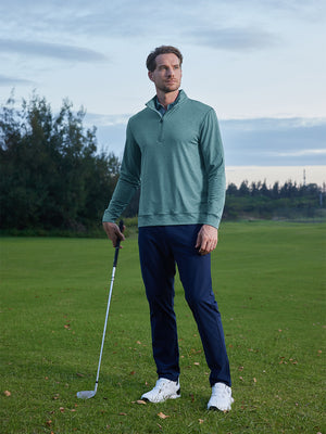 Model leaning on a golf club on course, styled in quarter zip melange pullover with relaxed aqua heather tone