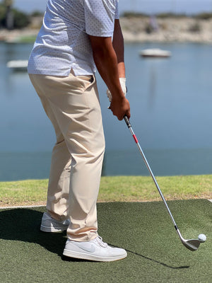 A model wearing light khaki water resistant everyday pants plays golf on the golf course